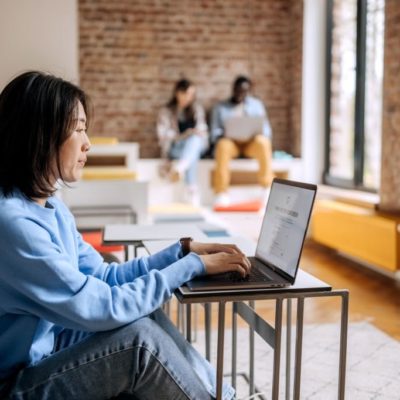 Young casually clothed woman shopping online for clothes in office cafeteria